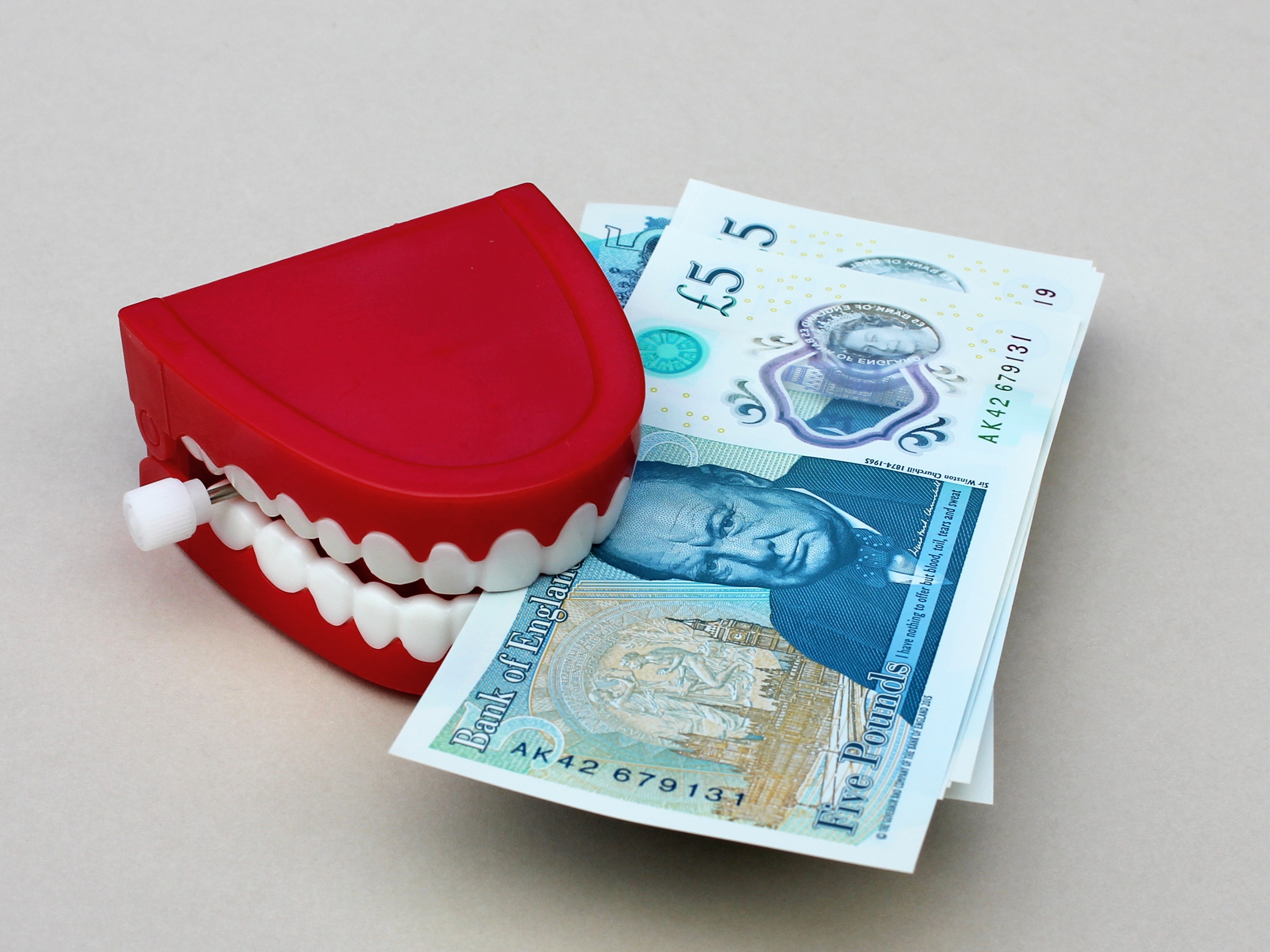 Red teeth holding money at the Glasgow orthodontics clinic.